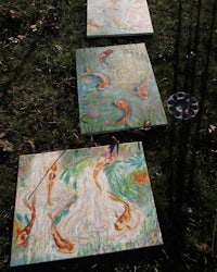 three paintings on a grassy area