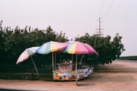 colorful umbrellas on the side of a dirt road