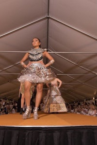 a woman in a dress walking down a runway