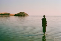 a person standing in the water near an island