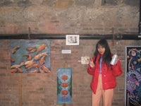 a woman standing in front of a brick wall with paintings