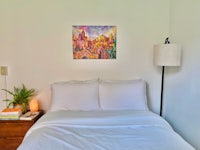 a bed in a room with a painting on the wall