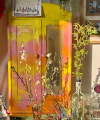 a yellow painted cabinet with flowers in it