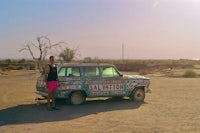 a man standing next to a car in the desert